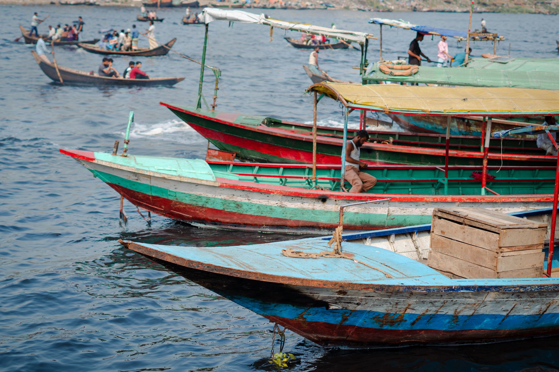 Vibrant fishing boats in various colors floating on a peaceful lake, bustling with activity.