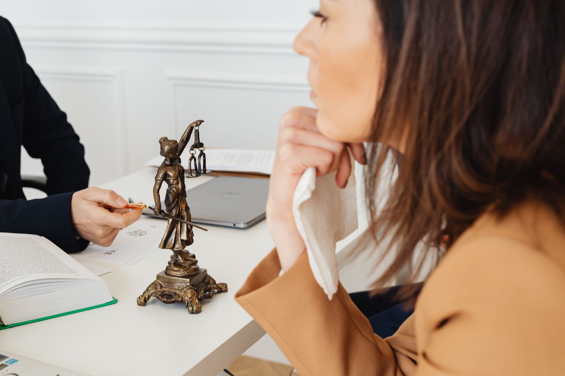 Un cadre professionnel avec une statue de la Justice, deux personnes discutant de questions juridiques.